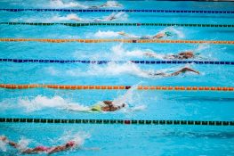 Swimmers compete in an outdoor pool race, showcasing athleticism and sportsmanship.