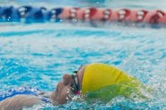 Swimmer with colorful cap in a bright blue pool, showcasing athletic energy.