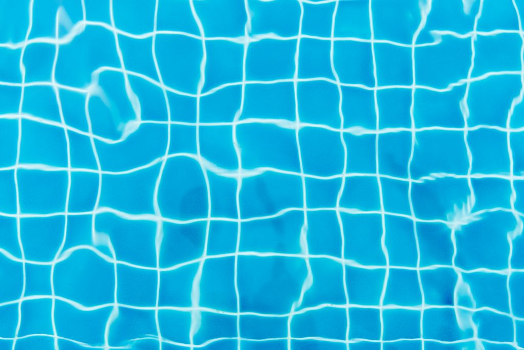 Top view of a swimming pool with vibrant blue water and tile patterns.