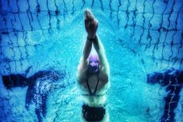 Captivating underwater shot of a swimmer in a pool with clear blue water.